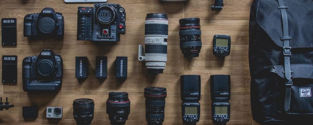 A series of cameras and lenses equipment laid out flat on the floor