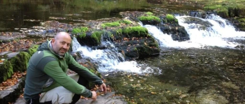 Chris Evans the founder of Waterfalls Ways, sat next to a waterfall