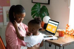 Ann-Marie Kinlock with a child in front of a desk with a laptop