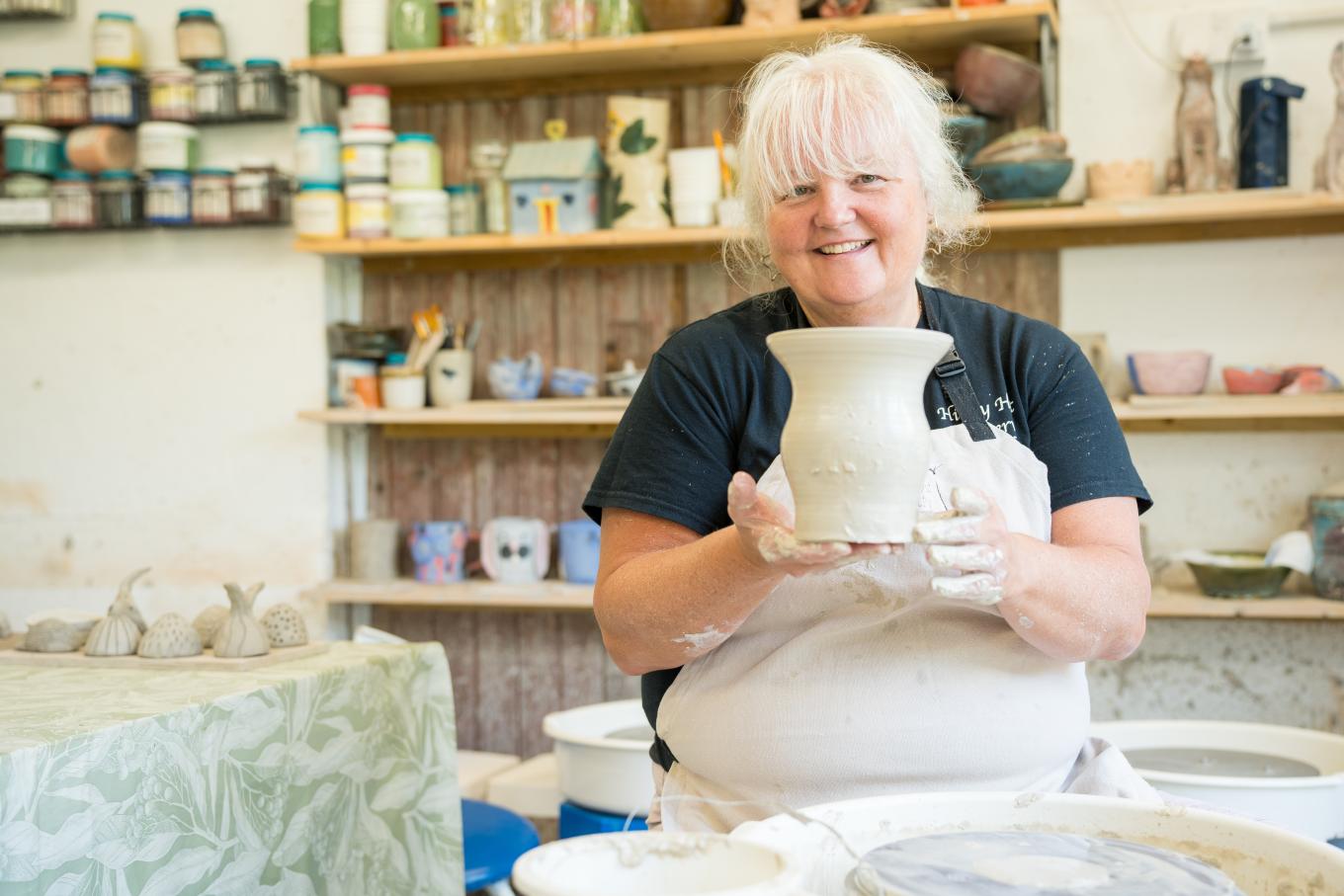 Owner of Hippy Hut Pottery holding a clay pot