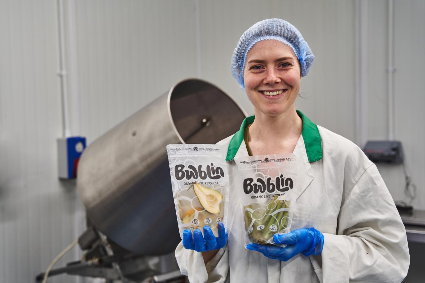 Founder of Bwblin in a factory setting holding products