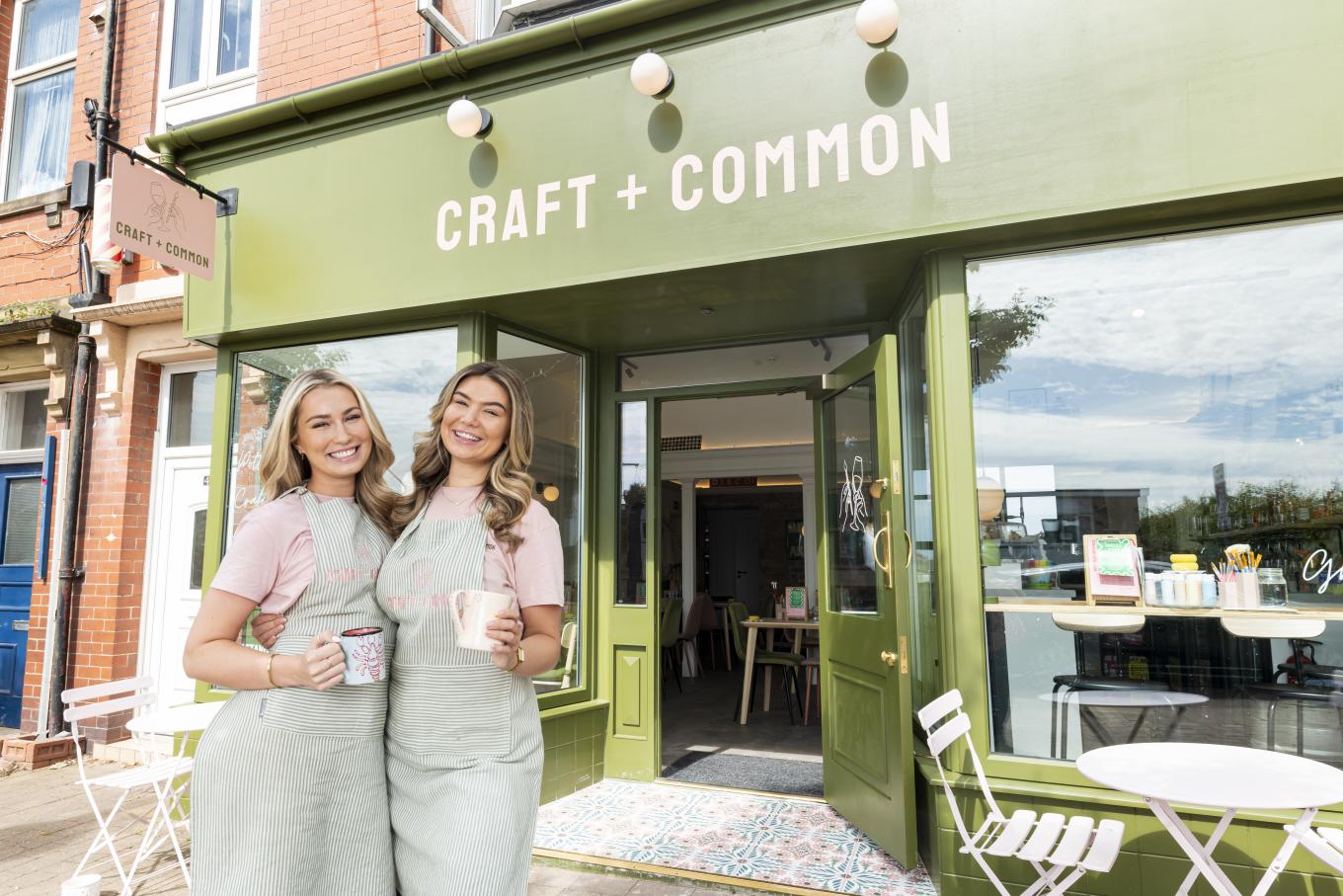 Founders of Craft +Common in front of their business holding coffee mugs