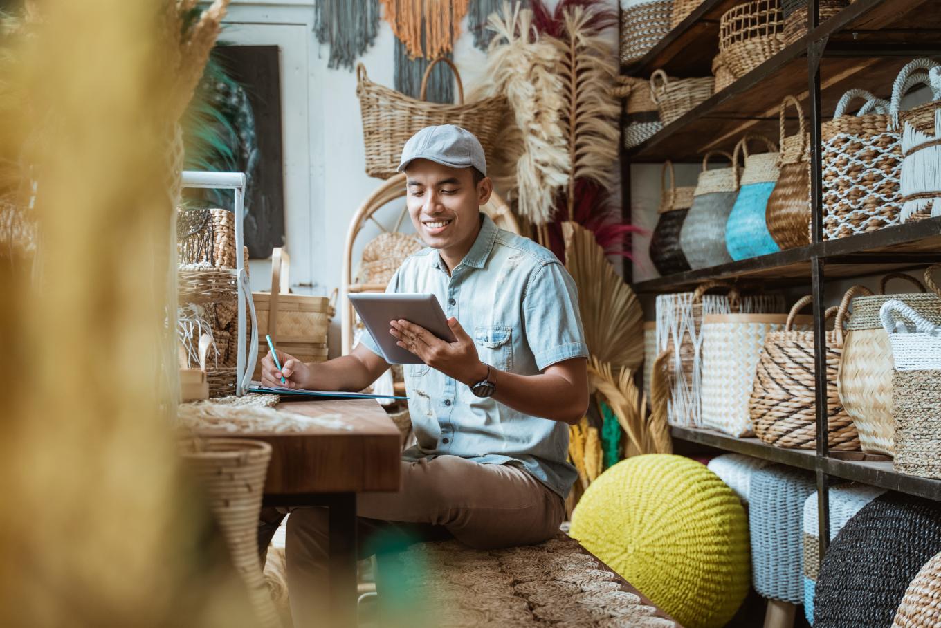 shop keeper smiling whilst looking at ipad behind a counter