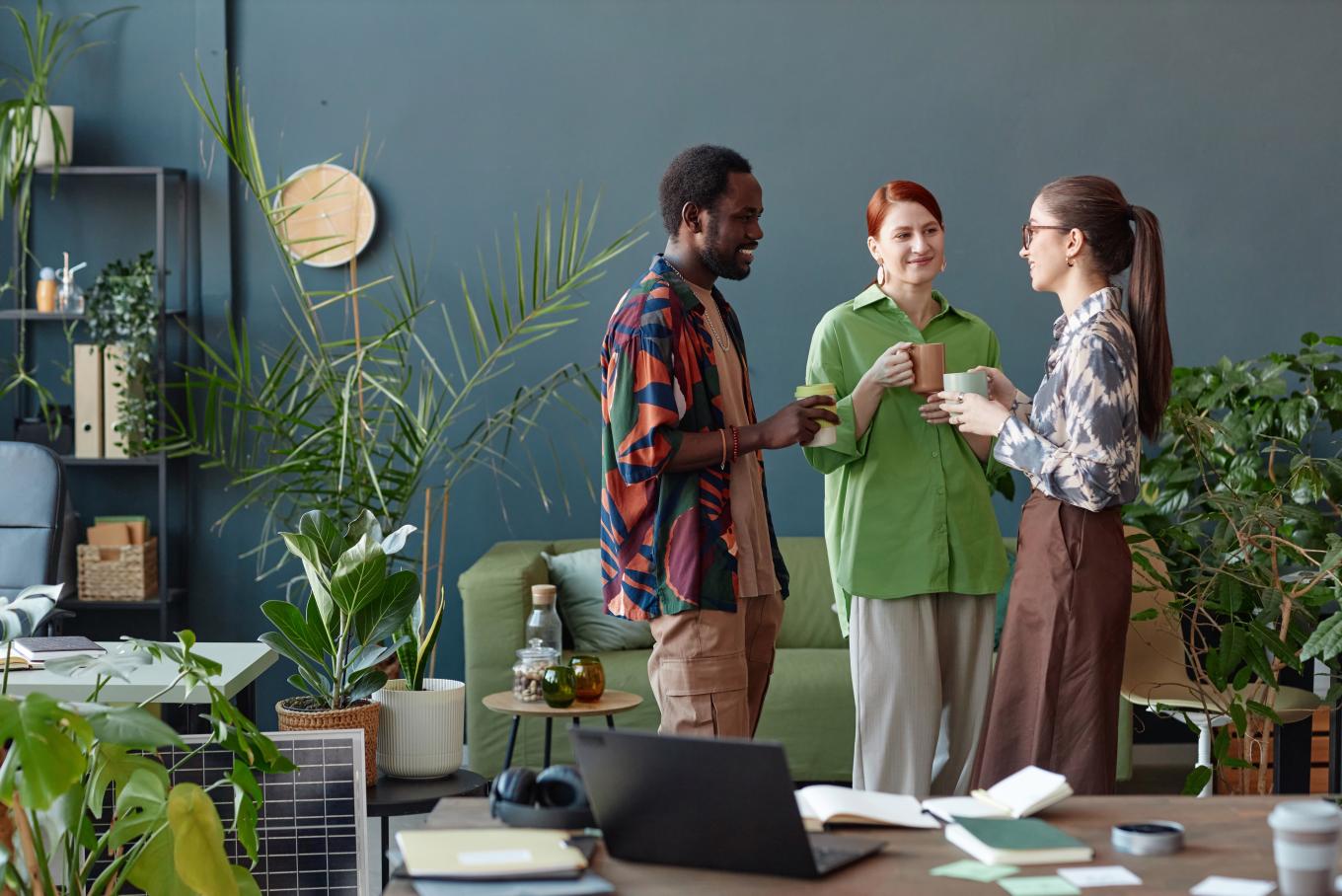 An image of a male and two females standing up in conversation in a relaxed environment