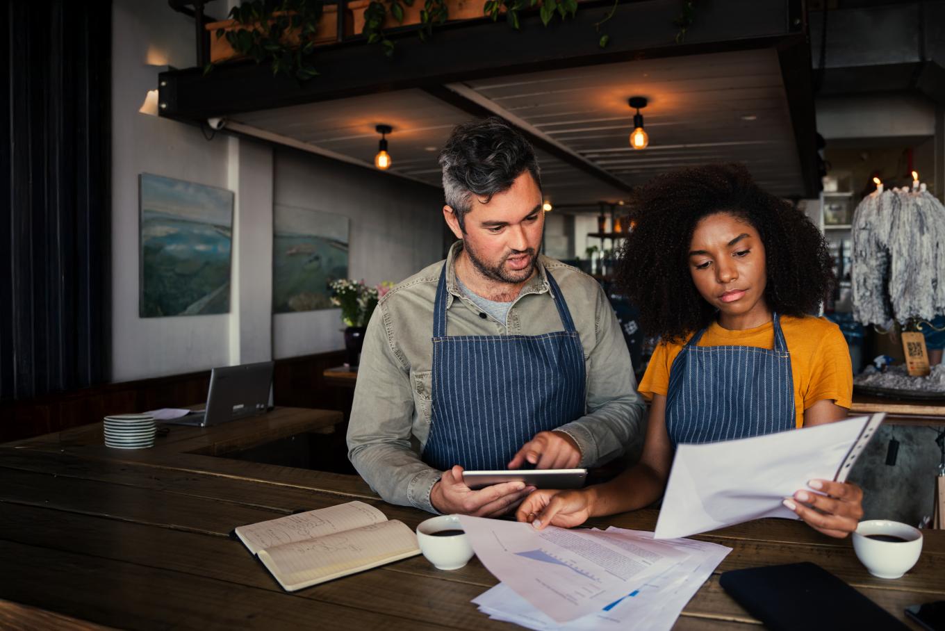 Male and female stood at a table reviewing paperwork in a darkly lit environment
