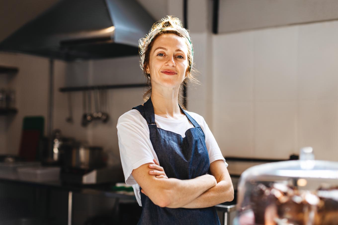 A female wearing an apron in a bakery type environment