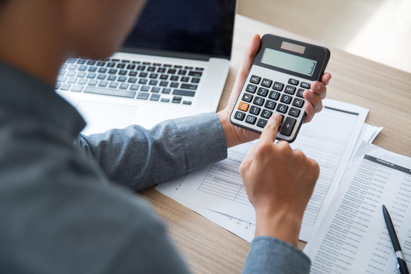 A man sat at a desk using a calculator