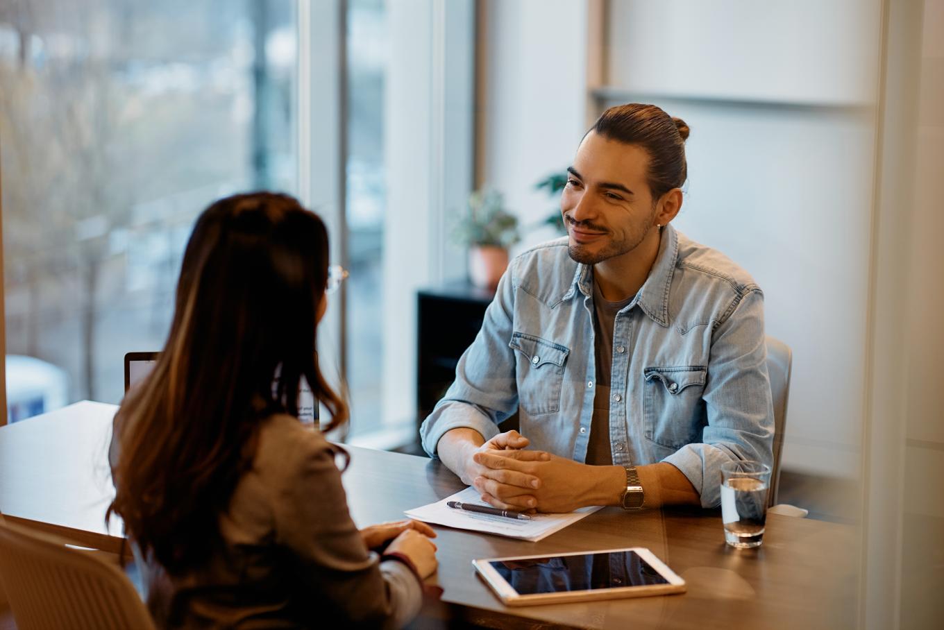 A male and female sitting opposite one another in an conversational/interview style interaction